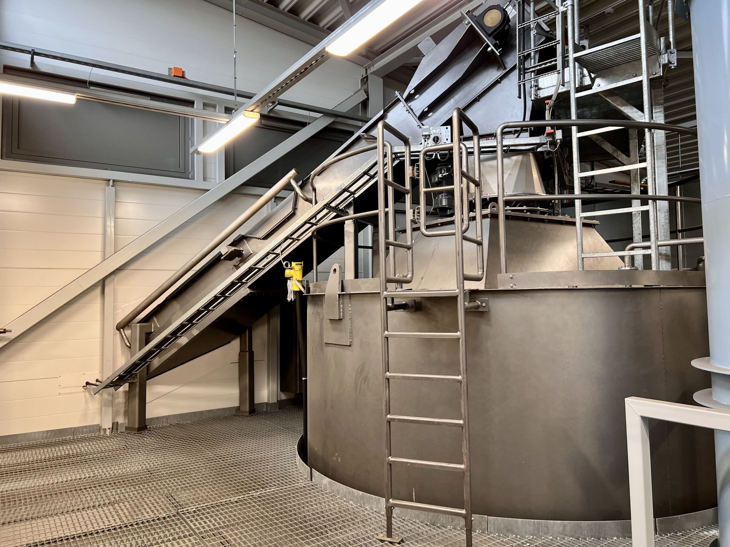 Gray silo and chain conveyor on top of silo.
