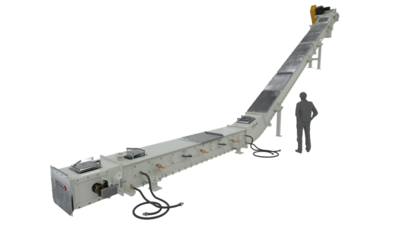 A man standing beside a big cooled chain conveyor.