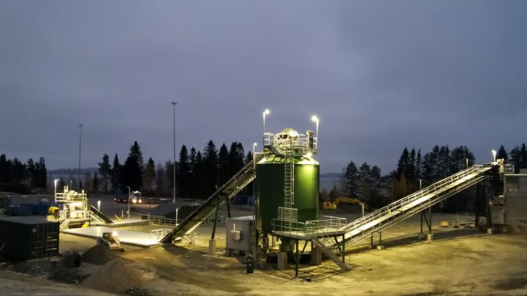 Bio oil refinery with green silo at night.