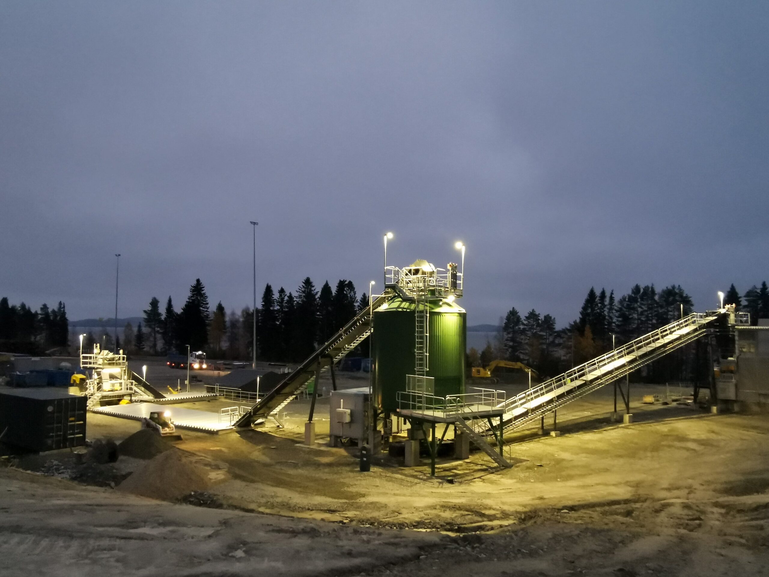 Bio oil refinery with green silo at night.