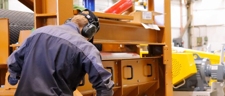 Konetekniikan opiskelija kokoamassa hihnakuljetinta.